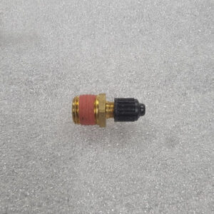 A small brass and plastic valve component on a gray surface.